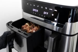 Medidor de consumo eléctrico junto a una Air Fryer FOXBOX Genus Aeris en una cocina moderna.